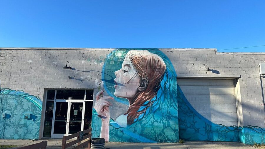 Side of a building featuring a mural of a woman smoking a cigarette, located in Asheville's River Arts District.