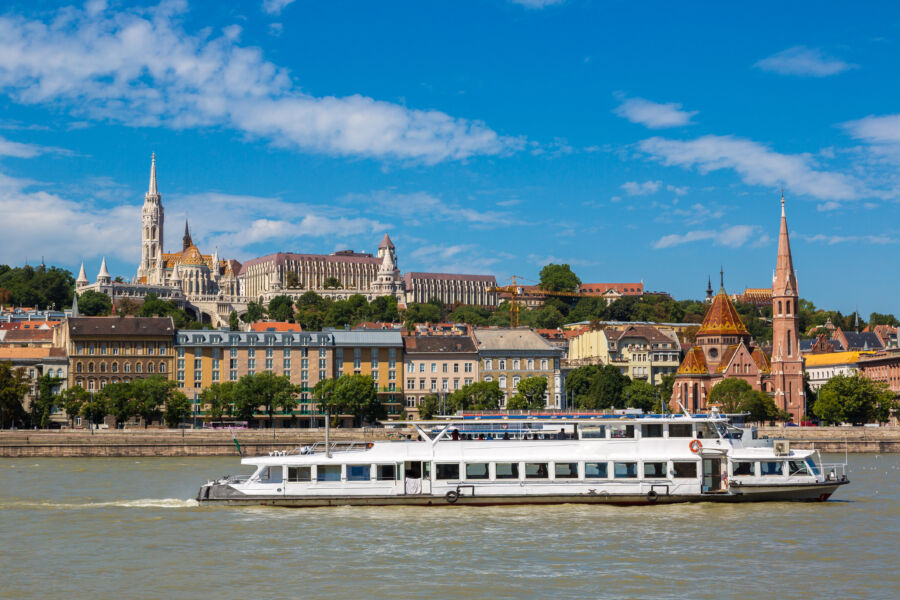 River cruise ship navigating the Danube River in Budapest, surrounded by the city's iconic landmarks