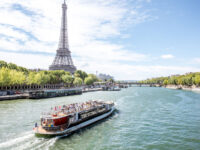 Scenic view of the Eiffel Tower and Seine River, featuring a tourist boat gliding through the picturesque Paris landscape