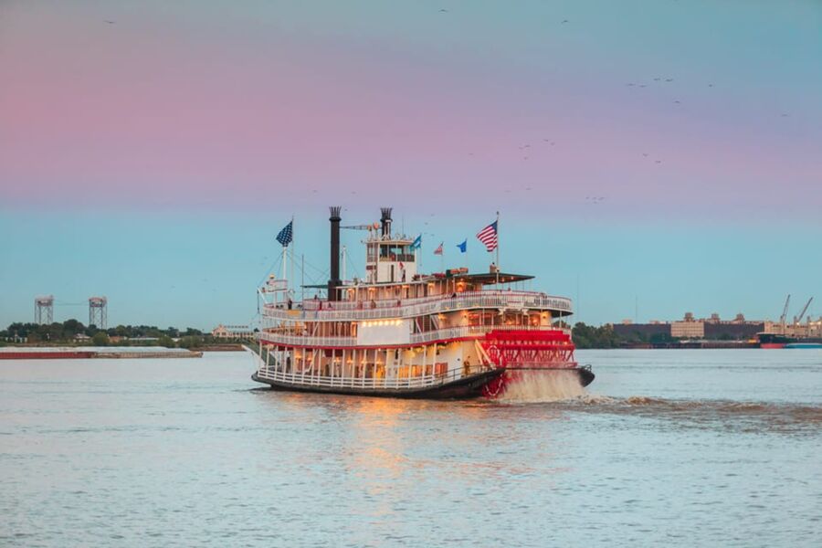 Twilight Orleans riverboat cruise, paddlewheel steamer, serene evening waterscape, nostalgia, adventure.
