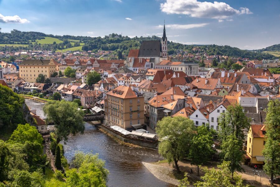 Picturesque European town with river, hills, church spire, vibrant rooftops, and serene ambiance.
