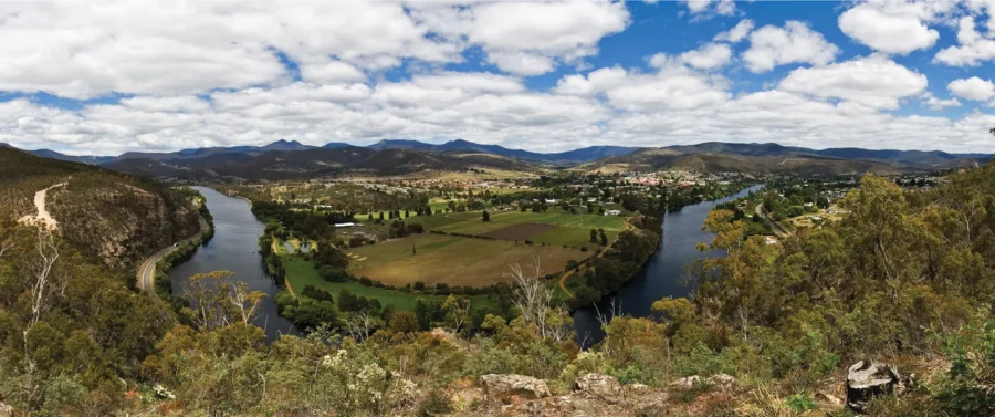 Scenic Derwent River valley landscape with farmland, town, blue sky, and distant mountains.