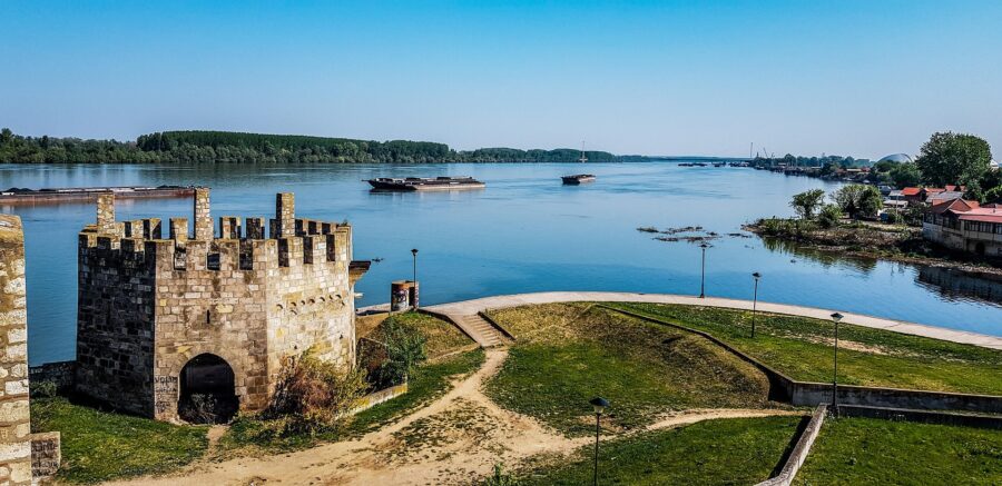 River landscape with ancient stone tower, reflecting waters, lush greenery, and historic significance.