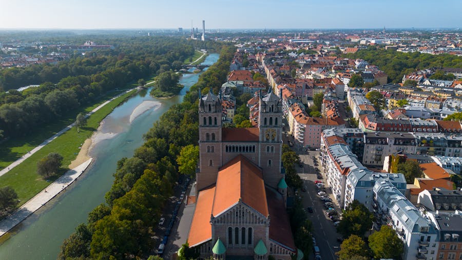 Aerial city view of riverside basilica with red-tile roof and green waterfront.
