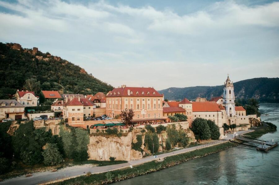 Hotel Schloss Dürnstein above Danube River, historic Austrian town, baroque church, scenic hills.