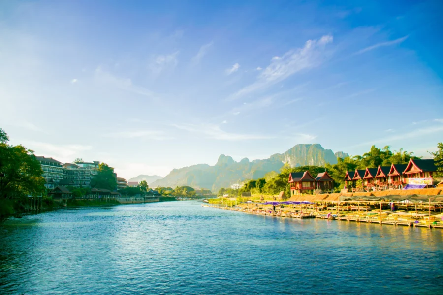 Scenic riverside resort town with traditional houses, modern buildings and karst mountains at sunset.