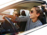 Two young women joyfully driving in a car during a road trip
