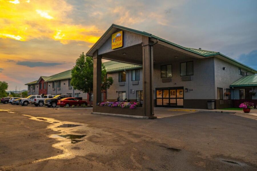Cozy hotel at sunrise/sunset with parking, greenery, and tranquil surroundings.