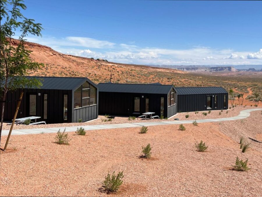 Three black cabins in the Arizona desert with a mountain backdrop at Roam America Horseshoe Bend.
