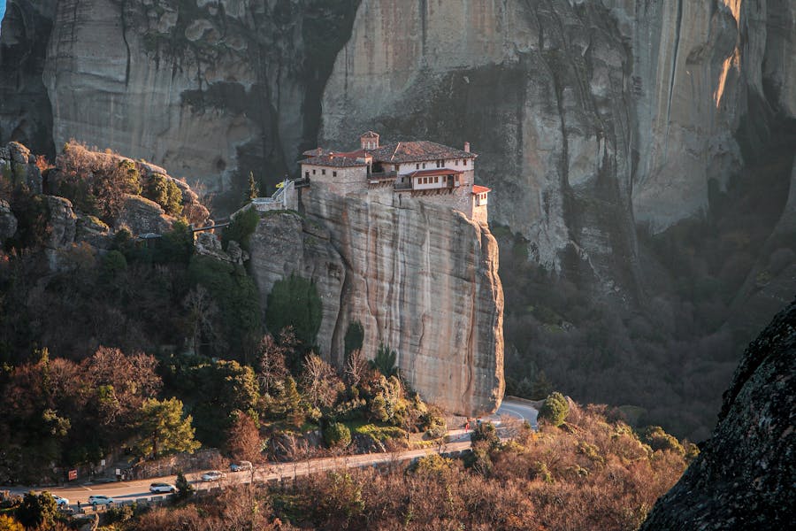 Roussanou Monastery perched on Meteora rock pillar in Greece, red-tiled cliffside monastery.