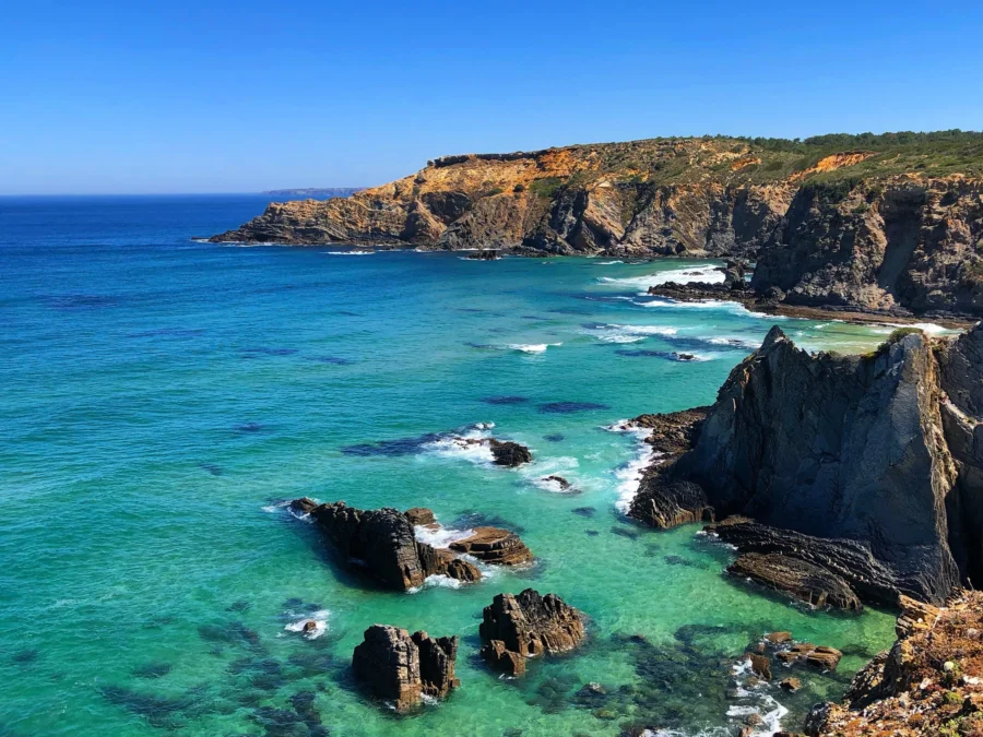 Vicentine Coast Natural Park: rugged rocky cliffs and turquoise sea under clear blue sky.