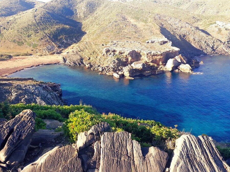 Rocky cove and turquoise bay viewed from cliff on Camí de Cavalls.