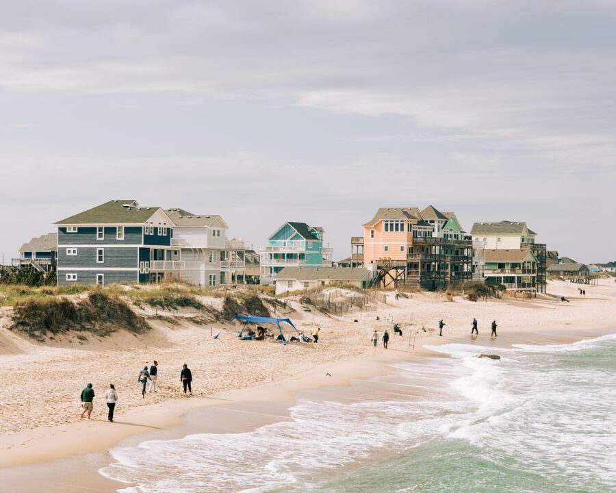 Rodanthe Pier stretches over the ocean, with waves crashing against its wooden supports under a clear blue sky.