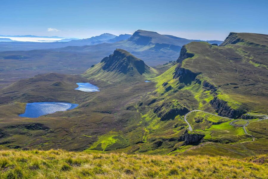 Scenic landscape of rugged hills, lakes, and mountains in the Quiraing, Scottish Highlands.