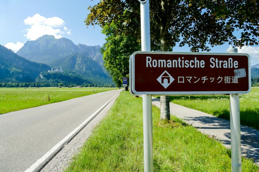 German road sign indicating the Romantic Road (Romantische Straße), surrounded by scenic countryside