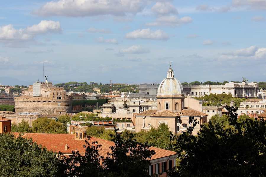 Sunlit Gianicolo panorama of Rome showcasing Castel SantAngelo, terracotta roofs, and domes.