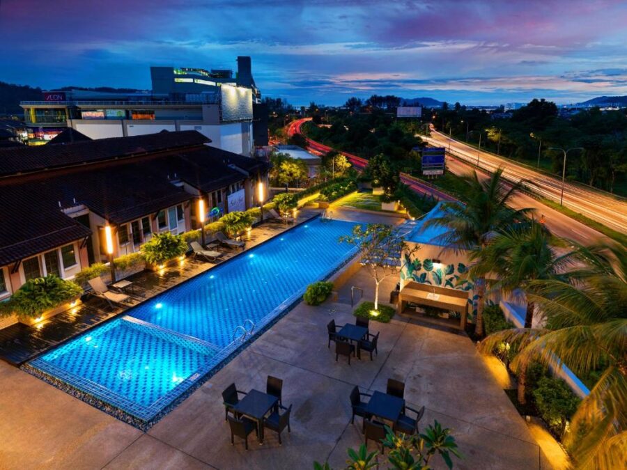 Rooftop hotel infinity pool at twilight overlooking city lights, luxury resort deck and highway.