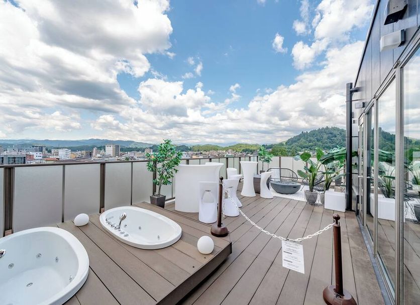 Luxury Takayama rooftop terrace with hot tubs, city skyline views, mountains and modern outdoor spa.