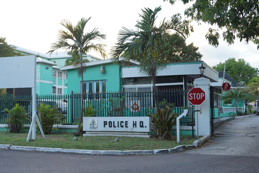 Police station with a stop sign and a fence, identified as the Royal Bahamas Police Headquarters.