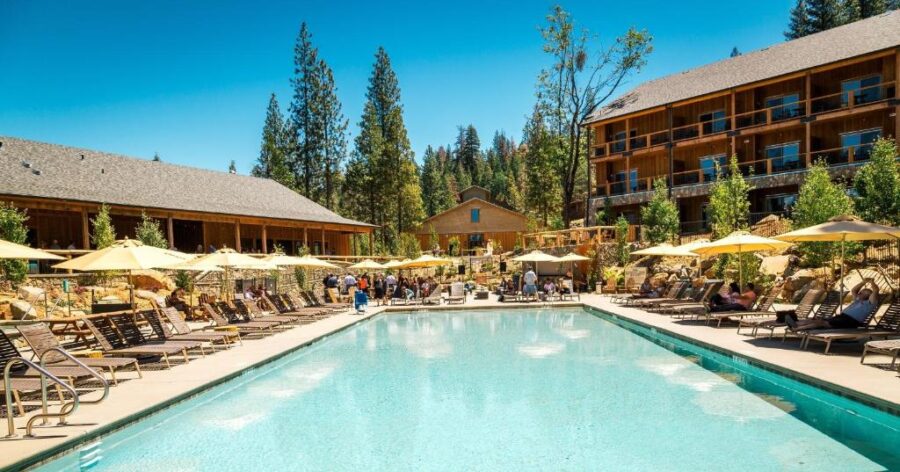 The pool at Rush Creek Lodge, surrounded by trees and mountains, offers a serene retreat in Yosemite National Park.