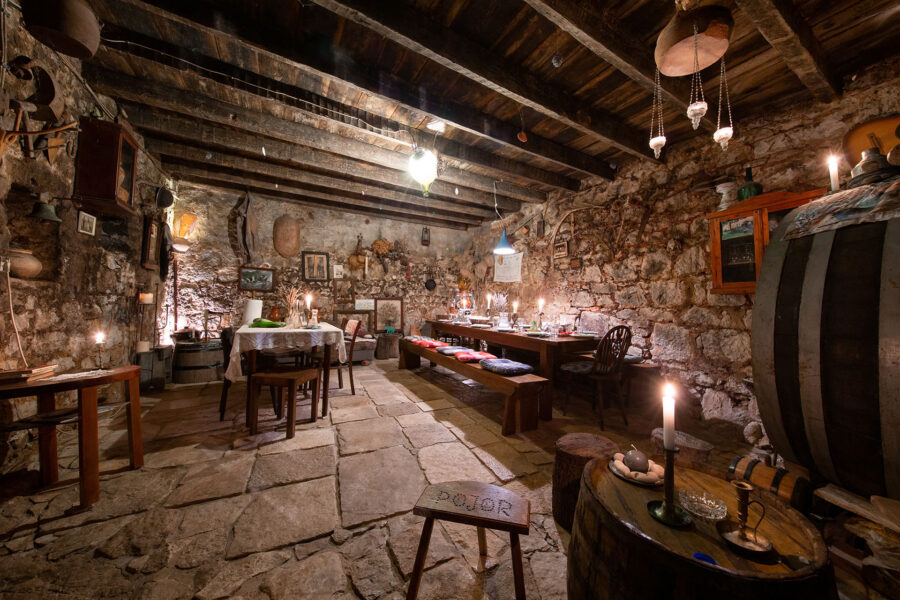 Rustic dining room with stone walls, wooden beams, vintage decor, and a cozy, inviting atmosphere.