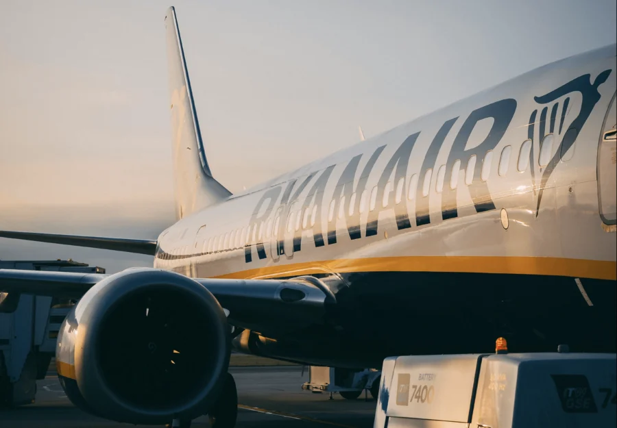 Ryanair plane on tarmac during golden hour, showcasing airline branding and airport activity.