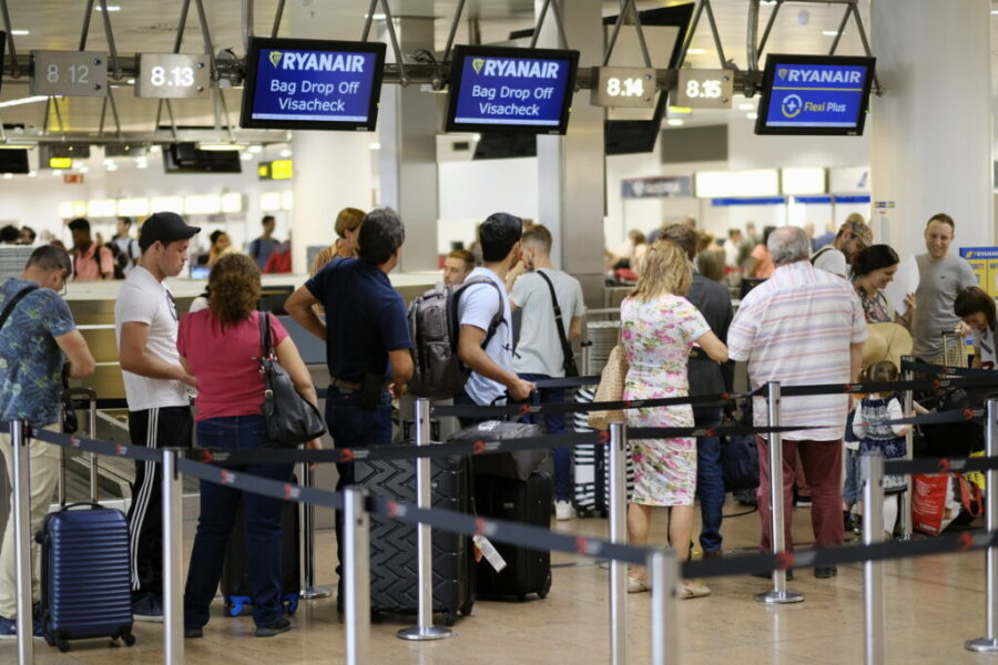 Ryanair cabin crew strike at Brussels Airport, travelers queue during labor rights protest.
