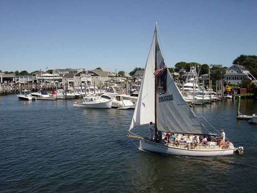 Serene Hyannis marina scene with the sailboat Evensong, American flag, and bright blue sky.