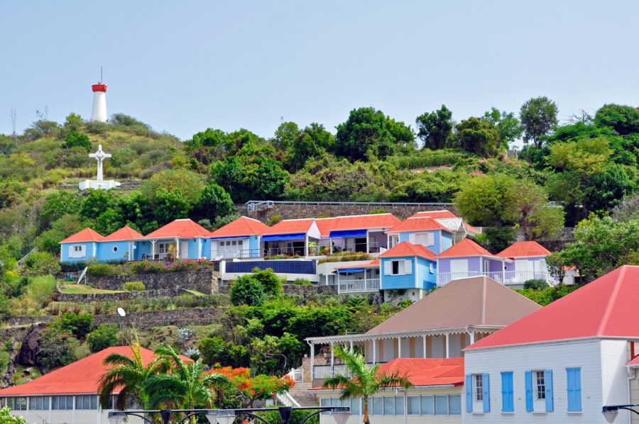 Scenic view of Saint Barthelemy in the Caribbean, featuring a prominent lighthouse against a clear blue sky.