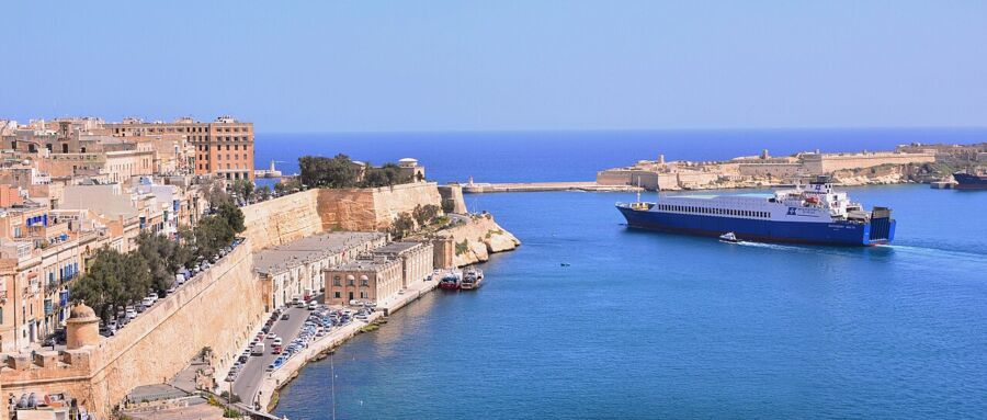 Ferry navigates the waters of Salerno, with a stone wall visible nearby, showcasing the beauty of the Amalfi Coast.