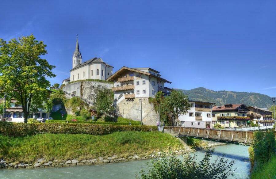 Scenic view of the Salzach River winding through Kaprun, Austria, with charming buildings and natural landscapes nearby