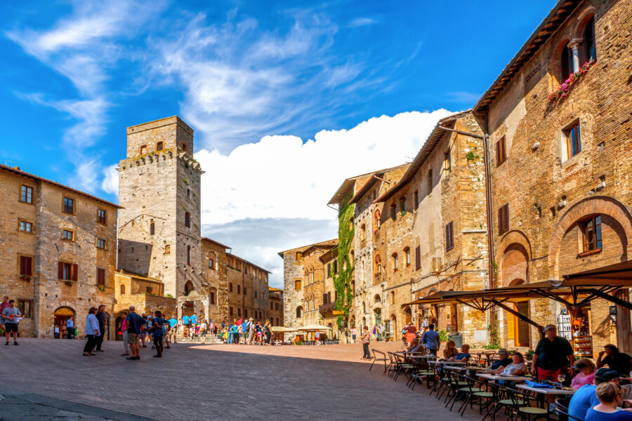 San Gimignano Plaza in Italy, featuring medieval architecture and bustling visitors enjoying the vibrant atmosphere