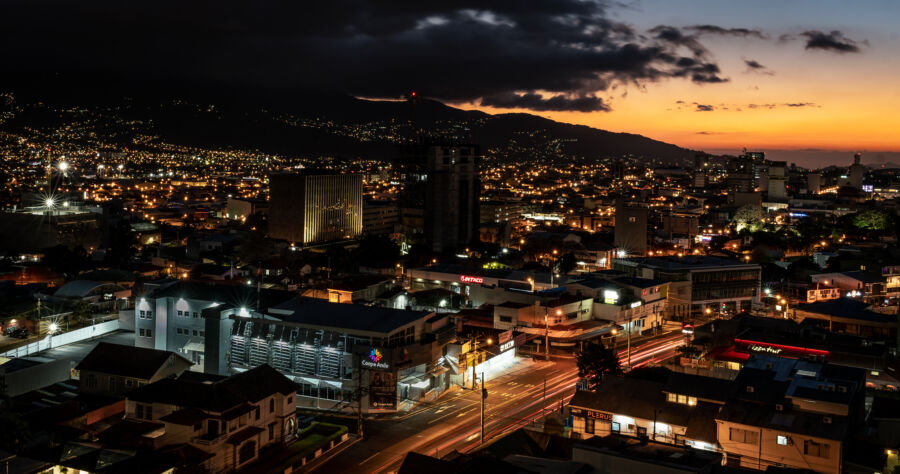 Night view of San Jose, Costa Rica, showcasing illuminated buildings and vibrant city lights against a dark sky