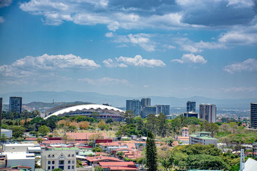 Panoramic view of San José, Costa Rica, showcasing the city's skyline against a backdrop of mountains and blue sky