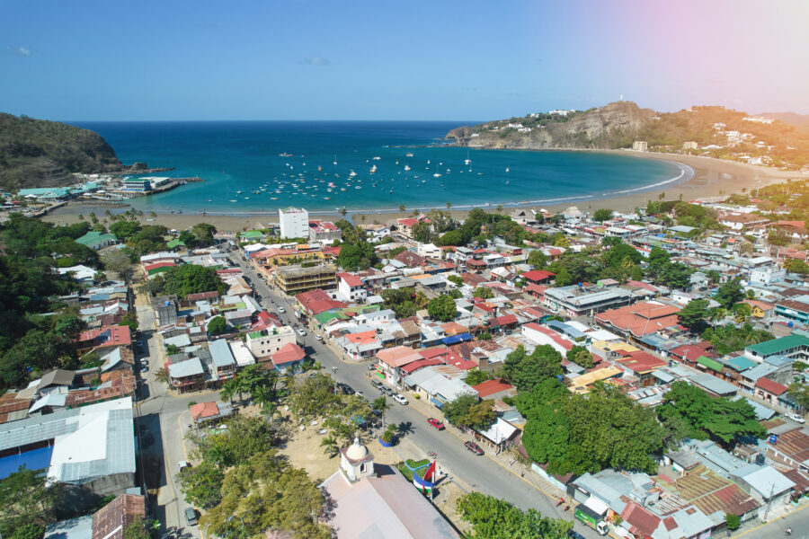 Aerial view of San Juan del Sur Beach, showcasing golden sands, turquoise waters, and lush green hills in the background