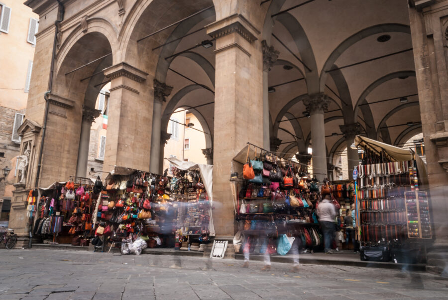 Leather goods showcased at the San Lorenzo market in Florence, Italy, featuring bags, wallets, and belts in various colors 