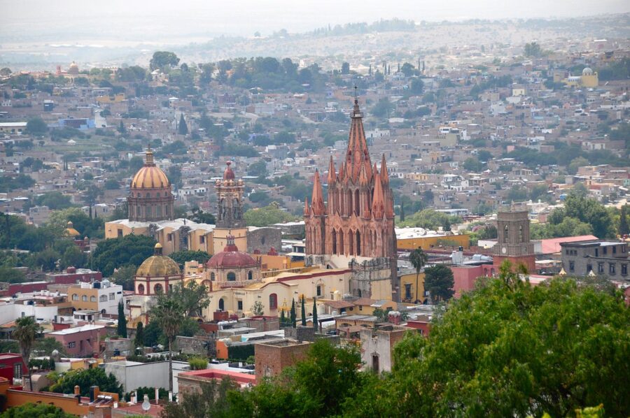 Aerial view of San Miguel Allende, showcasing the cityscape and surrounding hills under a clear blue sky.
