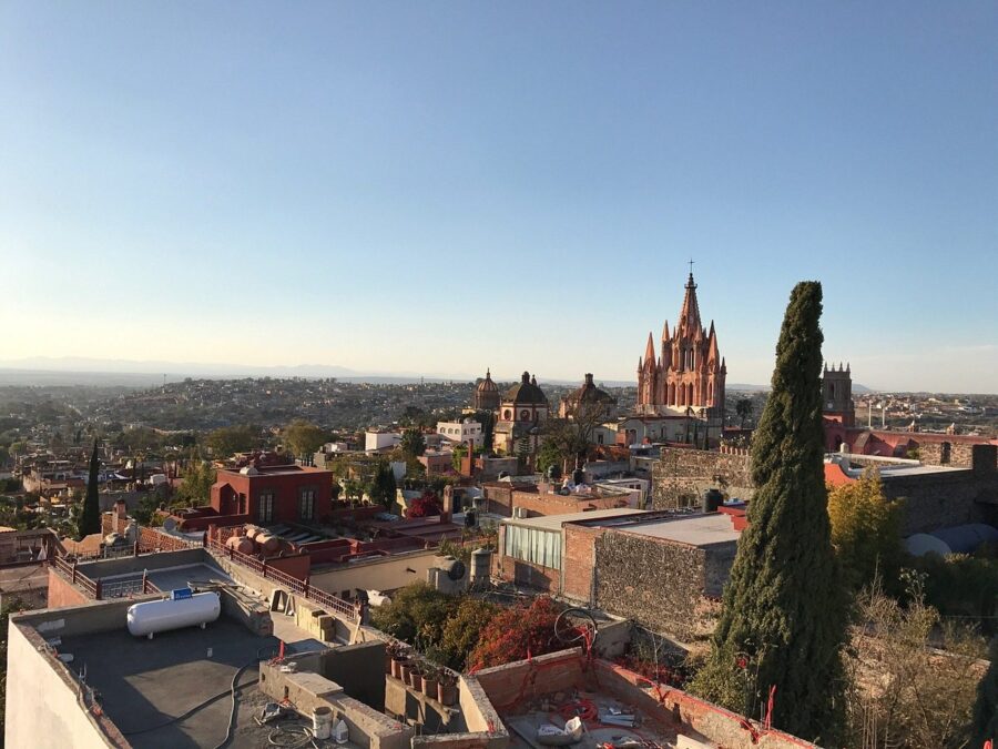 Panoramic view from a rooftop in San Miguel Allende, showcasing colorful buildings and lush landscapes under a clear sky.