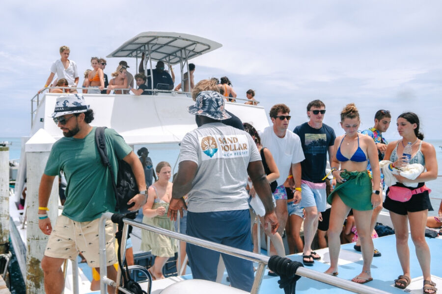 People enjoying a boat ride at Sand Dollar Beach Resort in the Bahamas, with a man in a hat among them.