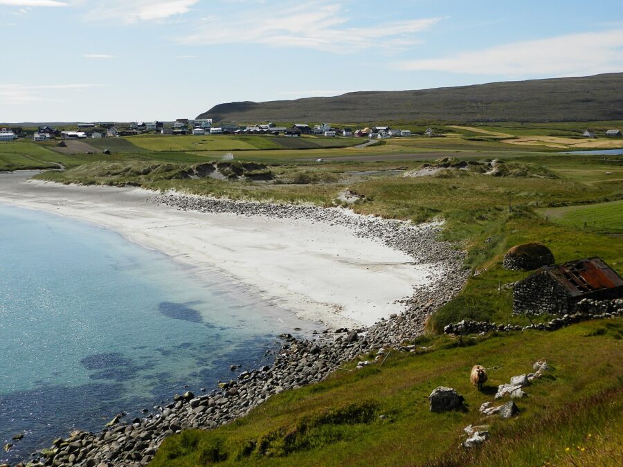 Scenic grassy hillside on Sandoy, Faroe Islands, featuring vibrant green terrain and gentle slopes.