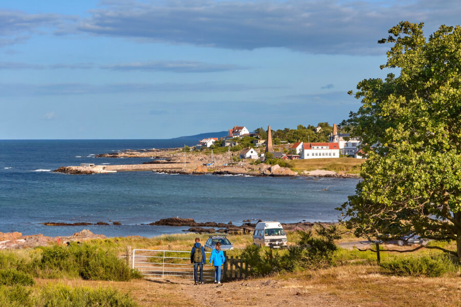 Panorama of Svaneke, Denmark, showcasing red-roofed houses and granite rocks on a sunny summer day.