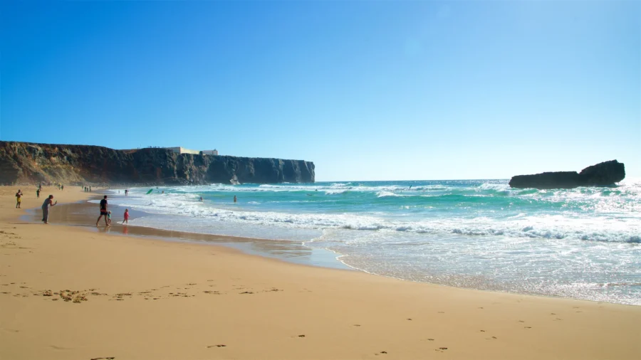 Costa Vicentina beach with golden sand, cliffs, rocky outcrop and rolling waves.