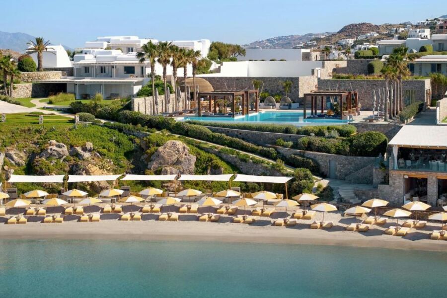 The beach at Santa Marina Resort is framed by elegant white buildings, showcasing a luxurious coastal atmosphere.