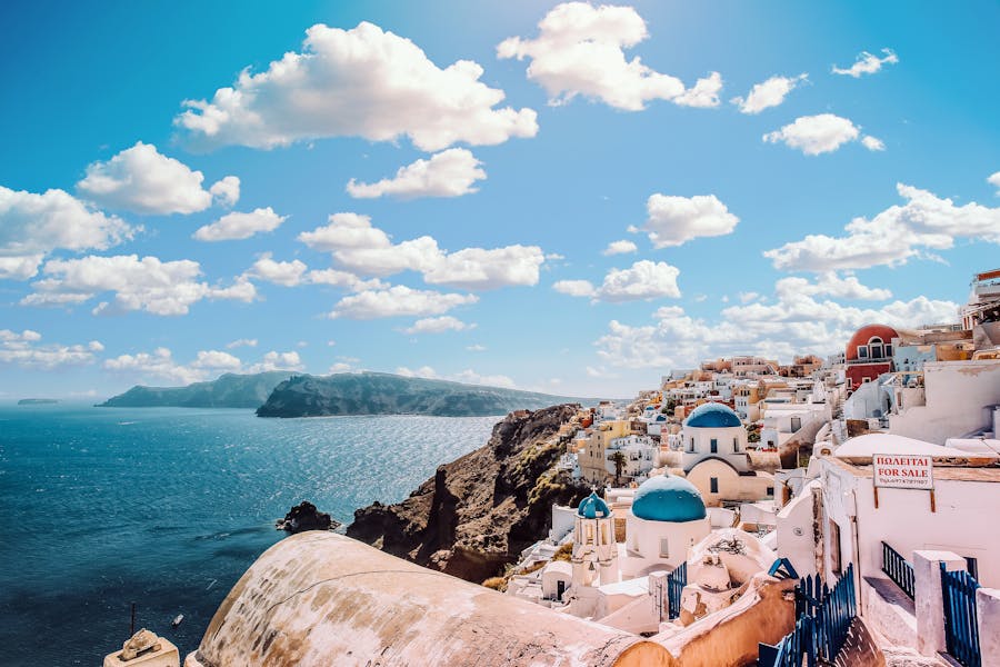 Stunning Santorini coastal scene with white buildings, blue domes, and Aegean Sea view.