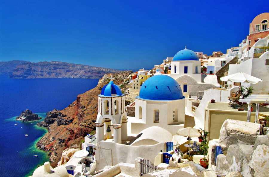 Stunning view of Santorini, Greece, showcasing iconic white and blue buildings against a clear sky and sparkling sea