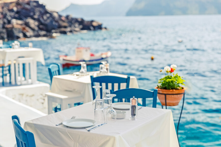 Seafront restaurant in Santorini, Greece, with a table set for dining overlooking the Aegean Sea