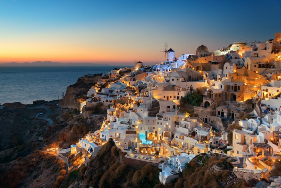 Night view of Santorini's skyline, featuring illuminated white buildings and a starry sky over the Aegean Sea