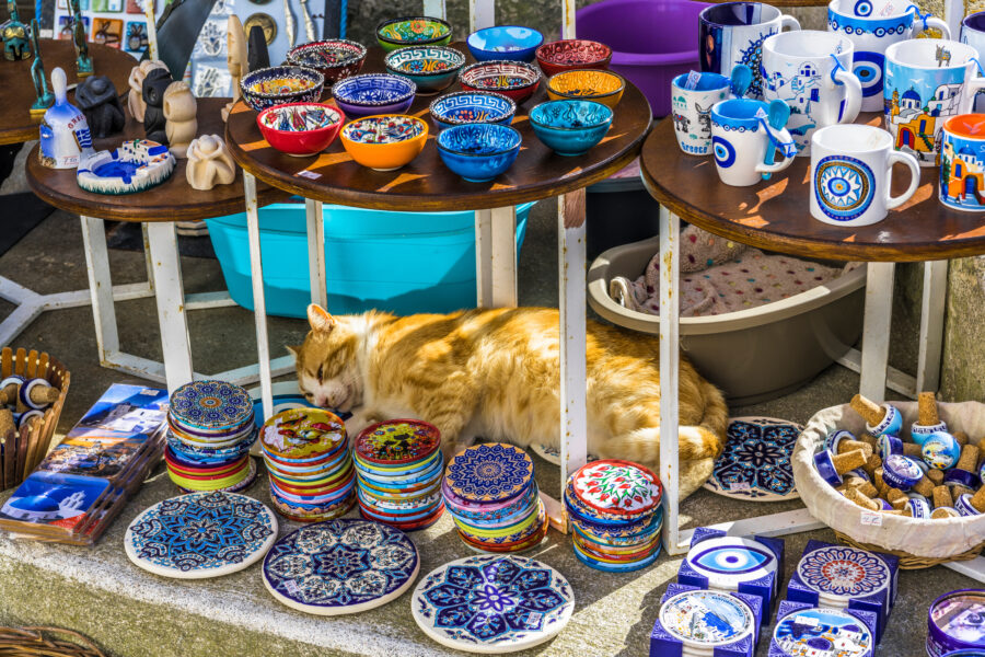 Sleeping cat nestled among colorful street souvenirs in Santorini, showcasing the vibrant local culture