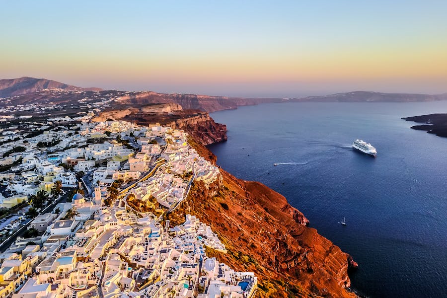 Santorini sunset view with white buildings, blue domes, and Aegean Sea.