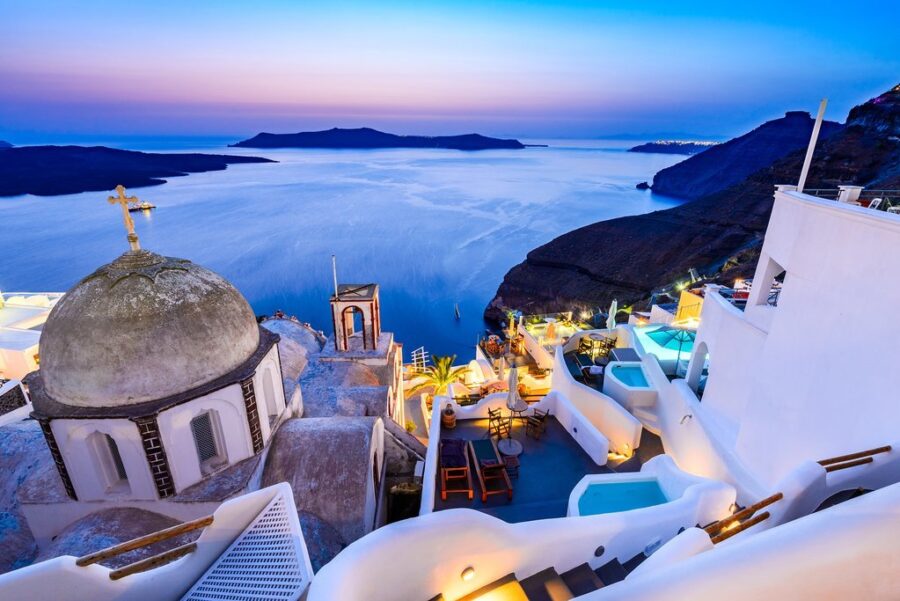 Santorini twilight view with iconic white dome, sunsets, Aegean Sea, and Greek architecture.